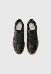 Baskets noires avec une tige en cuir verni et une boîte à orteils noire pailletée. Présente des accents texturés contrastants et des lacets noirs.