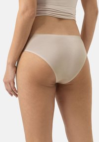 Beige stretch cotton hipsterunderkläder med måttlig täckning, slät textur och minimala sömmar. Etikettinformation synlig på midjebandet.