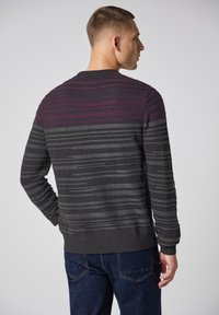 Pull en tricot de couleur gris foncé avec des rayures horizontales de violet et de gris clair. Col rond et finitions côtelées aux poignets et à l'ourlet.