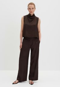 Brown sleeveless top with a cowl neckline, paired with wide-leg trousers in matching color, featuring smooth texture and minimal design.