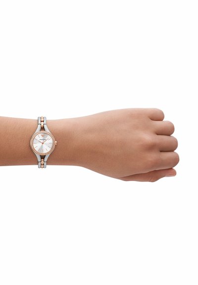 Silver and rose gold wristwatch with round white face, sparkling bezel, and dual-tone metal link band. Fits snugly on a wrist.