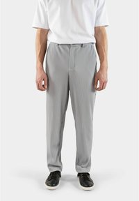 Grau gestreifte Hose aus leichtem Stoff mit lässigem Schnitt. Verf�ügt über einen klassischen Bund und Seitentaschen. Kombiniert mit schwarzen Sneakers.