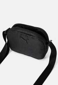 Black padded crossbody bag made of durable fabric. Features a zip closure, adjustable strap, and subtle embossed logo design.