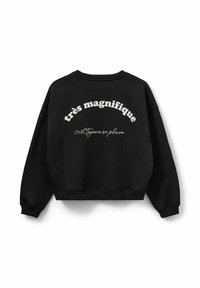 Černá mikina s cropped designem, s bílým textem na zádech: "très magnifique" tučně a "c'est toujours un plaisir" v kurzívě.