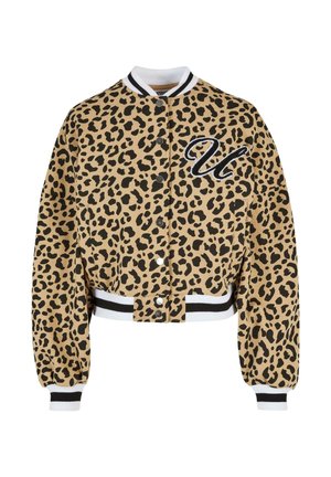 Avkortet beige leopardmønstret jakke med svarte flekker. Har knappeåpning, hvit og svart stripet krage, og brodert bokstav "U."