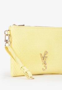 Borsa a mano gialla con texture e motivo a diamante, dotata di logo in metallo dorato "V3" e tracolla rimovibile. Chiusura a zip nella parte superiore.
