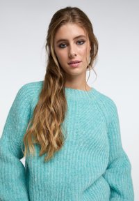 Maglione turchese a maglia con texture a costine, scollatura rotonda e maniche larghe, realizzato in morbida lana pelosa.