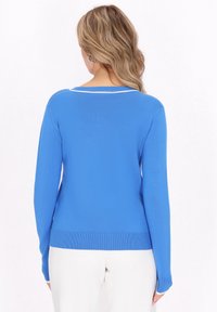 Suéter ligero azul de manga larga, con un dobladillo acanalado y un acento blanco en contraste en el cuello. Textura suave.
