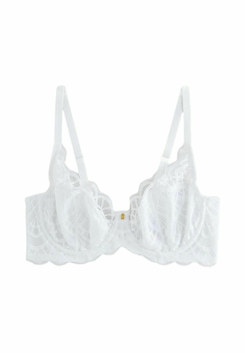 Reggiseno bianco in pizzo con bordo scallopato, dotato di coppe semi-trasparenti e spalline regolabili. Dettaglio in metallo dorato al centro anteriore.