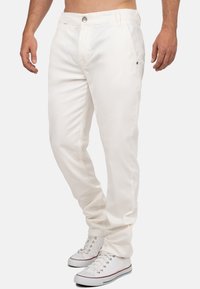 Witte katoenen broek met een recht ontwerp, voorzien van een sluiting met een knoop aan de voorkant, zijzakken en een zachte textuur. G gedragen met witte sneakers.