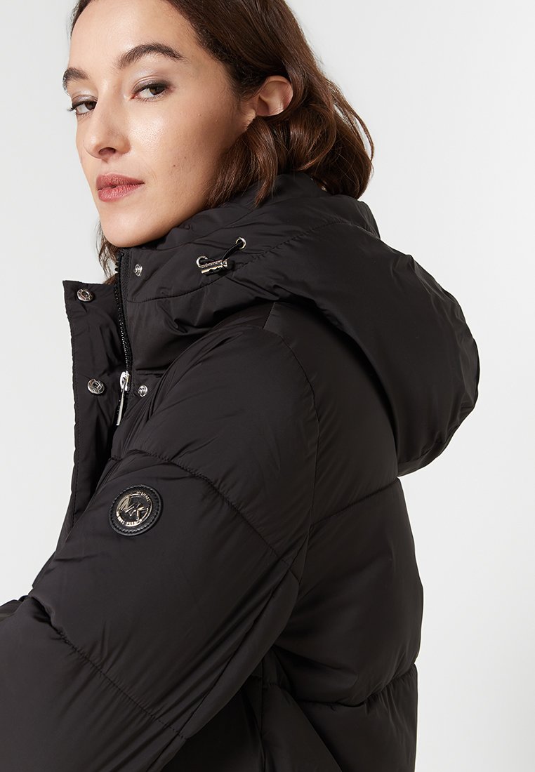 Schwarze Daunenjacke mit Kapuze, mit Reißverschluss, glänzendem Stoff, Seitentaschen und einem runden Logopatch am oberen Arm.