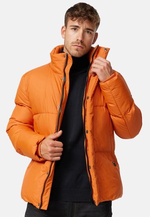 Orange Pufferjacke mit hohem Kragen, Reißverschluss und Knopfdetails. Mit gestepptem Textil und Fronttaschen.