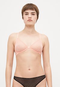 Pink, sheer triangle bra with diamond pattern, adjustable straps, and underwire. Paired with black, sheer underwear featuring a similar pattern.