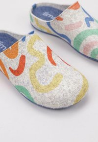 Zuecos de fieltro con una base de color gris claro y patrones abstractos coloridos en naranja, amarillo, verde y azul. Plantillas azules visibles.