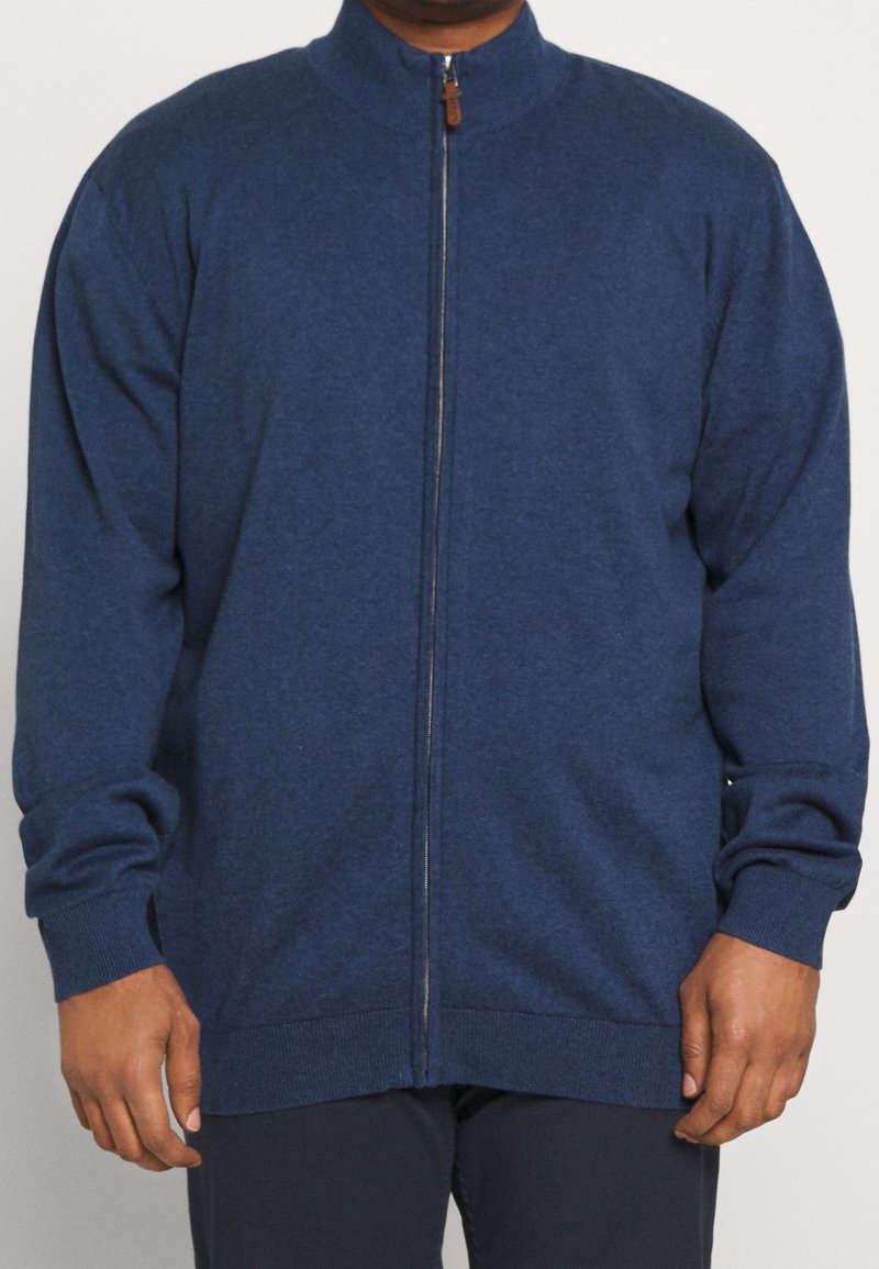 Námorně modrá zipová mikina vyrobená z měkké látky, s vysokým límcem, žebrovanými manžetami a lemem. Jednoduchý design bez viditelných vzorů.
