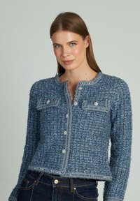 Cardigan blu in tweed con un motivo testurizzato, scollatura rotonda e bottoni decorativi. Presenta tasche frontali con dettagli in cucitura.