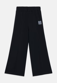 Svart vide bukser med elastisk midje, med et sydd detalj og en brodert "86" aksent på ett ben. Jevn tekstur.