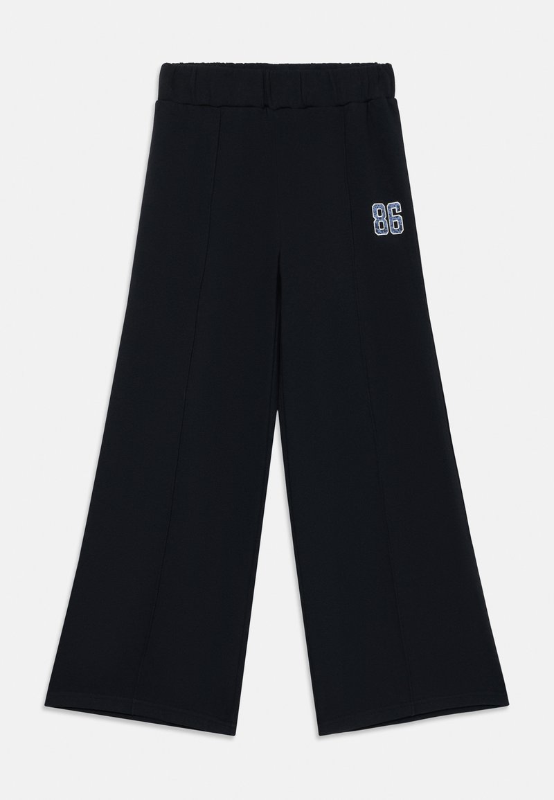 Svart vide bukser med elastisk midje, med et sydd detalj og en brodert "86" aksent på ett ben. Jevn tekstur.