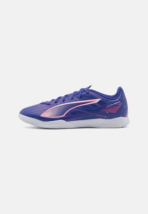 Zapatillas deportivas moradas con un diseño texturizado, con acentos en rosa y una suela blanca. Material ligero y silueta de perfil bajo.