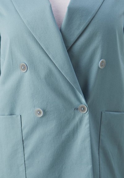 Blazer doppio petto di un delicato blu chiaro con tessuto morbido, dotato di due grandi bottoni e due tasche sulla parte anteriore.