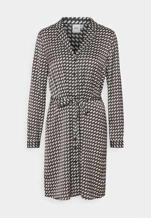 Black and white patterned dress with long sleeves, button-up front, collar, and adjustable waist tie. Features diagonal lines and geometric shapes.