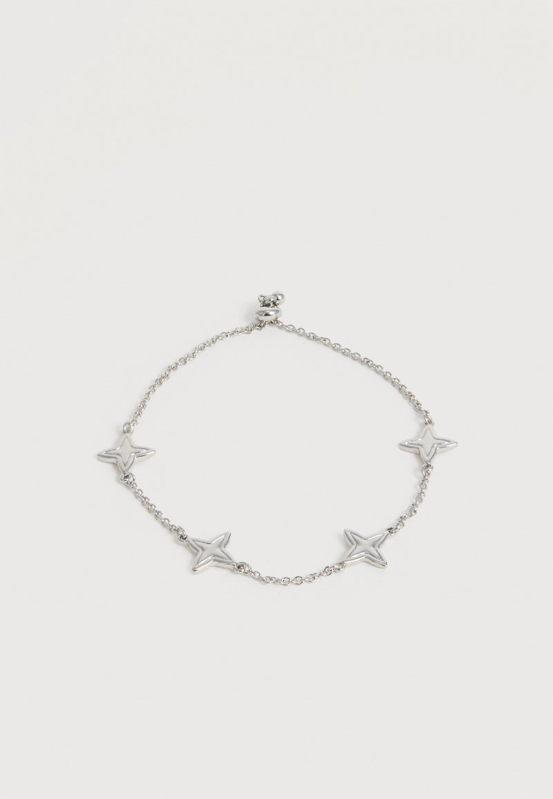 Bracelet chaîne en argent avec quatre breloques en forme d’étoile espacées uniformément le long de la chaîne sur un fond blanc uni.