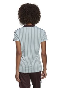 Polo shirt bleu clair à manches courtes avec des rayures verticales marron foncé et un col marron contrasté. Tissu lisse et coupe ajustée.