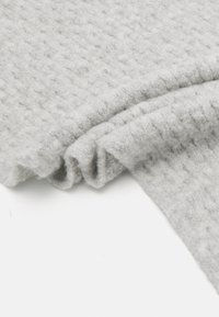 Têxtil de lã cinza com uma superfície macia e texturizada, apresentando um padrão em relevo, drapeado elegantemente com dobras visíveis.