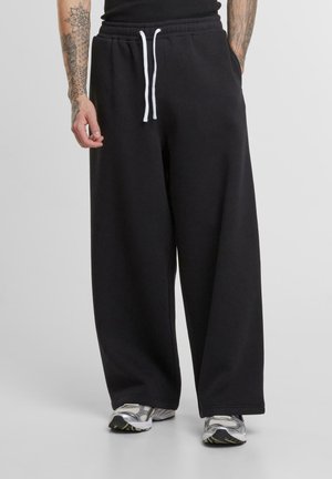Black wide-leg sweatpants made of soft cotton blend, featuring an elastic waistband with adjustable drawstrings and side pockets.