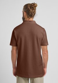 Polo shirt marrone a maniche corte con colletto, texture liscia e aperture laterali, mostrato da dietro.