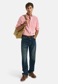Gestreepte rode en witte button-up shirt, blauwe jeans, bruine schoenen en een beige schoudertas. Casual outfit met verschillende texturen en kleuren.