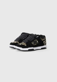 Black suede sneakers with camouflage accents, featuring a white midsole and black rubber outsole, lace-up design, and padded collar.