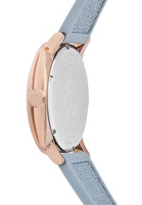 Rozā zelta nerūsējošā tērauda pulksteņa korpuss ar gaiši zilu gumijas jostu ar teksturētu dizainu. Korpusa aizmugurē ir iegravēta logo un detaļas.