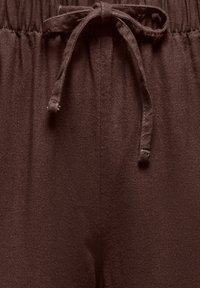 Pantalon en tissu marron avec une ceinture élastique et un cordon noué au centre devant.