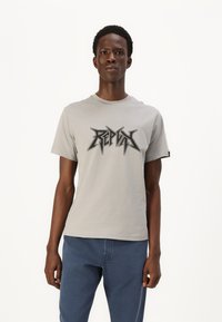 Grå kortærmet t-shirt med et iøjnefaldende sort grafisk print. Fremstillet af blødt materiale med en rund halsudskæring, kombineret med blå bukser.