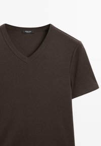 Bruine V-hals t-shirt gemaakt van zachte, gestructureerde stof. Korte mouwen en een klassieke pasvorm. Het label toont "Massimo Dutti" binnen de halslijn.