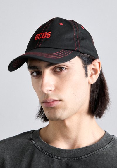 Casquette de baseball noire avec le logo "GCOS" brodé en rouge, coutures contrastantes rouges, visière courbée et design structuré.