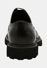 Chaussure en cuir noir avec un bout arrondi, un dessus texturé, un col rembourré et une semelle en caoutchouc noir robuste avec des rainures profondes pour une meilleure adhérence.