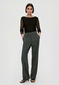 Black semi-sheer long-sleeve top paired with high-waisted gray wide-leg pants, featuring side pockets and a smooth texture. Black strappy heels.