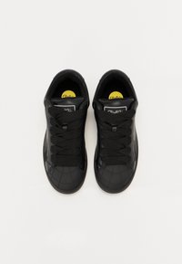 Sneaker neri con superficie testurizzata, punta tonda, design con lacci piatti e branding giallo sulla soletta.