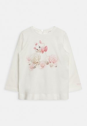 Langærmet cremefarvet skjorte med en katteillustration med en lyserød sløjfe, omgivet af lyserøde og hvide roser; blødt stof, rund halsudskæring.
