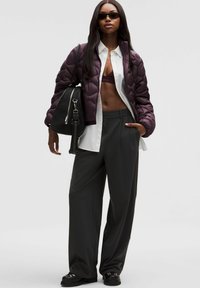 Bordowa pikowana kurtka, biała koszula z guzikami, ciemnoszare spodnie szerokie w nogawkach, czarna torebka i ciemne okulary przeciwsłoneczne. Gładkie tekstury i warstwowy wygląd.