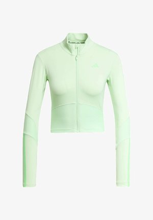Chaqueta deportiva corta de color verde claro con cuello alto y mangas largas, que presenta una textura acanalada y un sutil detalle de logo. Cierre de cremallera en la parte delantera.