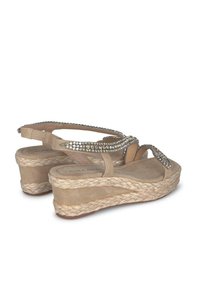 Beige wedge sandalen met een gevlochten jute zool, voorzien van een met juwelen versierde band en een verstelbare enkelband voor een veilige pasvorm en comfort.