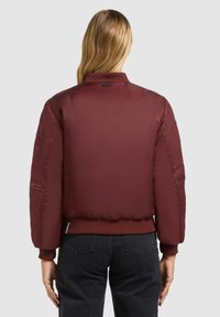 Bordeaux bomberjakke med ribbet krave og manchetter, der har en glat, shiny overflade og en sidelomme.