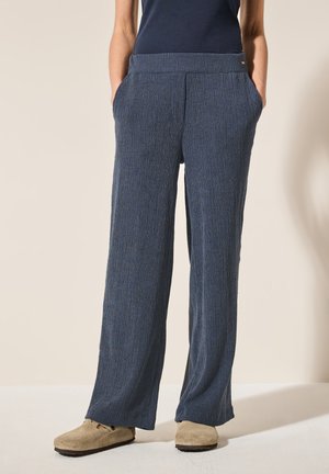 Pantaloni a gamba larga, di colore blu navy, realizzati in tessuto testurizzato con strisce verticali. Presentano due tasche laterali e una vestibilità rilassata in vita.