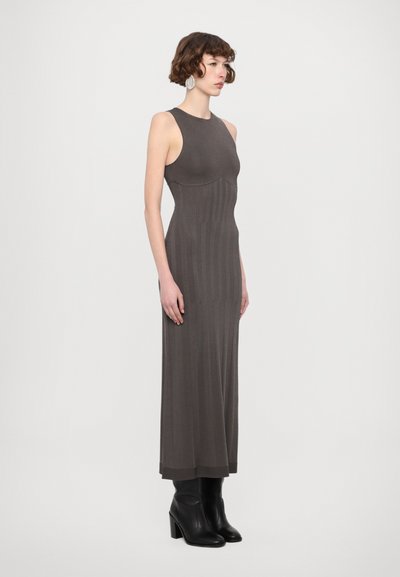 Sleeveless, form-fitting maxi dress in a dark taupe knit with vertical ribbing details; paired with knee-high black heeled boots.