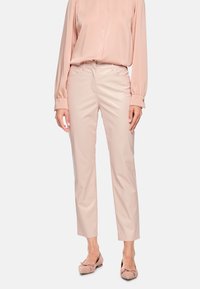 Hellrosa, schlanke Hose mit glatter, glänzender Textur. Verfügt über eine Taille mit mittlerer Höhe und Taschen. Kombiniert mit einer passenden hellrosa Bluse und flachen Schuhen.