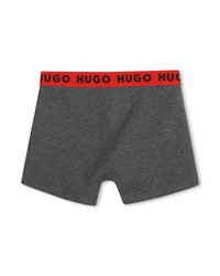 Σκούρα γκρι ανδρικά εσώρουχα boxer με κόκκινη μέση όπου επαναλαμβάνεται μαύρο το κείμενο "HUGO", τοποθετημένα επίπεδα σε λευκό φόντο.
