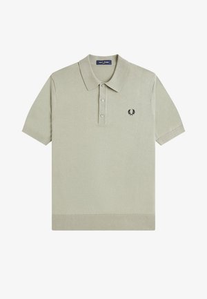 Lysebeige kortærmet poloshirt med tre knapper og et lille sort laurbærkranslogo på venstre bryst.